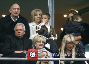 Romeo Beckham picks his nose as his mother Victoria looks on from the stands with sons Brooklyn and Cruz and...