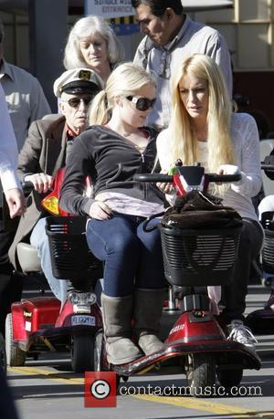 Hugh Hefner and Playboy bunnies, Anna Berglund and Caroline Clark, riding a mobility scooter whilst enjoying a day out at...