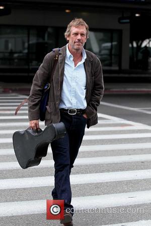 Hugh Laurie carrying his guitar as he arrives at LAX airport on a flight from London Los Angeles, California -...