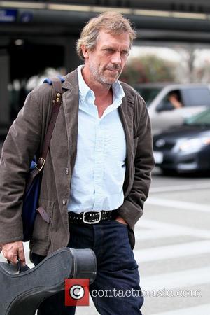 Hugh Laurie carrying his guitar as he arrives at LAX airport on a flight from London Los Angeles, California -...
