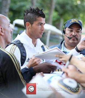 Real Madrid forward Cristiano Ronaldo signs autographs for fans as he leaves a training session with the rest of his...