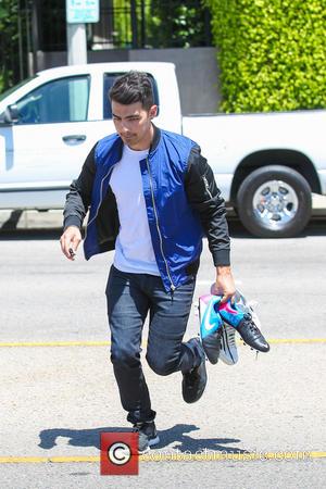 Joe Jonas - Joe Jonas carries his soccer boots before heading to watch the United States men's national soccer team...