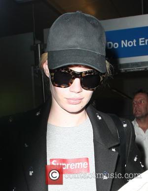 Iggy Azalea arriving at Los Angeles International Airport (LAX) wearing a Supreme t-shirt, long black coat, ripped jeans and tortoise...